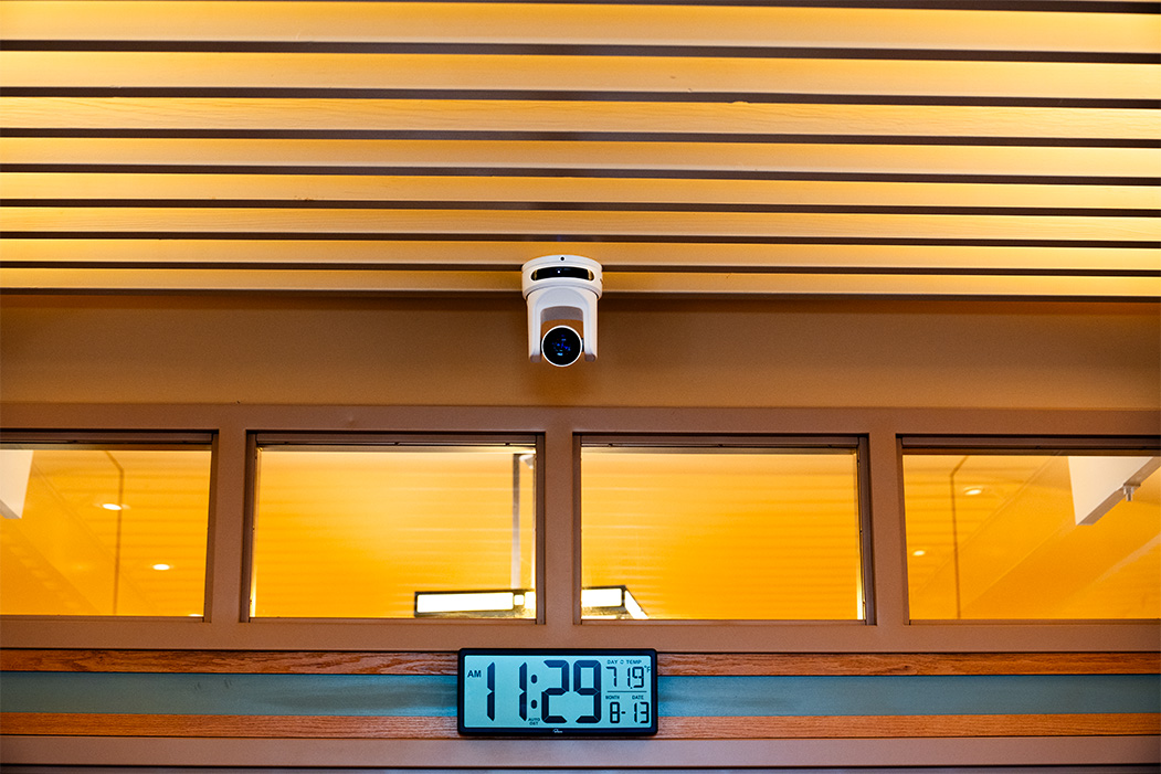 A broadcast PTZ Camera mounted to the ceiling of a slotted roof.
