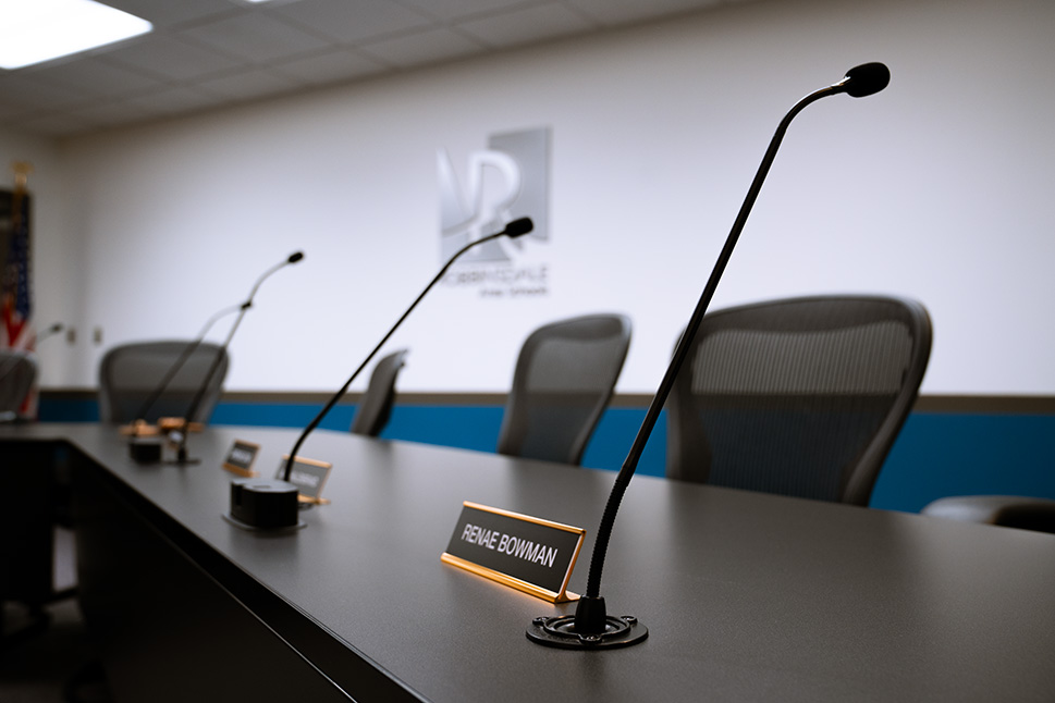 A boardroom table with multiple goose neck microphones in frame.